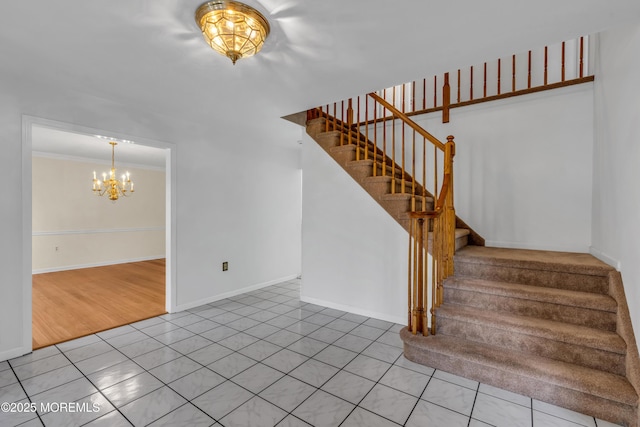 staircase with tile patterned floors, crown molding, baseboards, and a chandelier