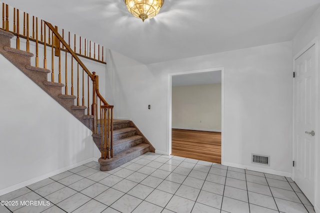 foyer featuring stairs, light tile patterned floors, baseboards, and visible vents