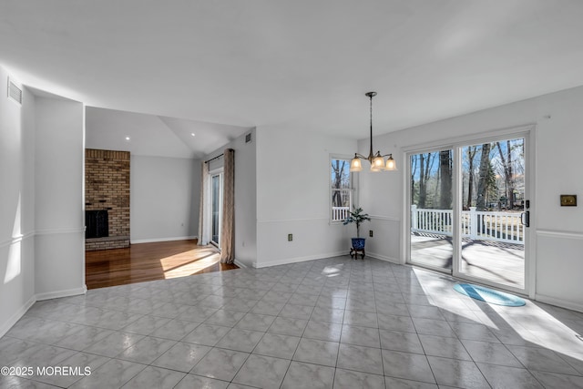 unfurnished dining area featuring light tile patterned floors, baseboards, a fireplace, vaulted ceiling, and a chandelier