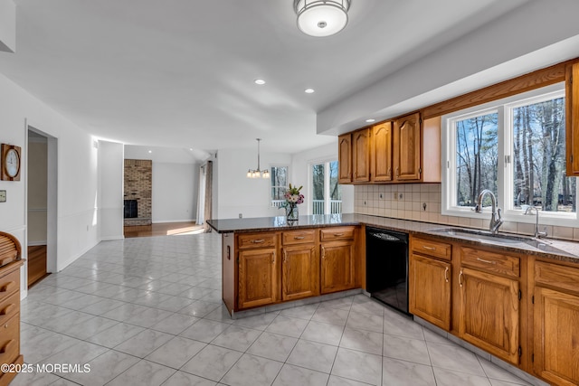 kitchen featuring brown cabinets, backsplash, light tile patterned floors, a brick fireplace, and dishwasher