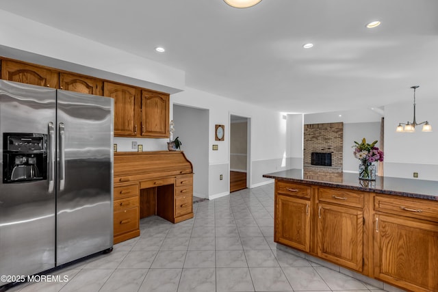 kitchen featuring brown cabinetry, recessed lighting, a fireplace, and stainless steel refrigerator with ice dispenser