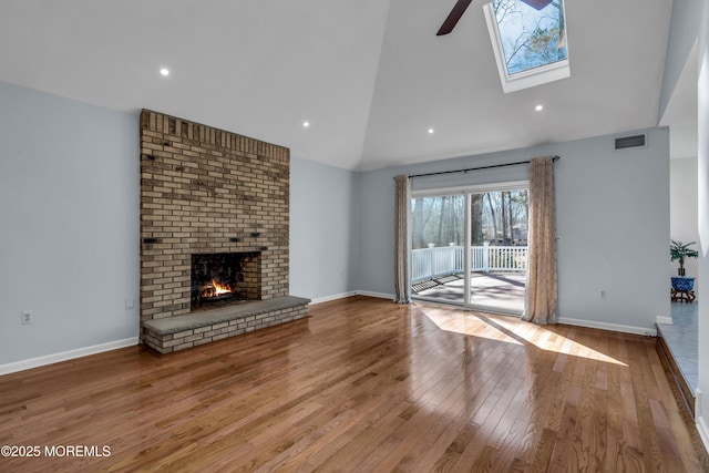 unfurnished living room with visible vents, high vaulted ceiling, wood finished floors, baseboards, and a brick fireplace