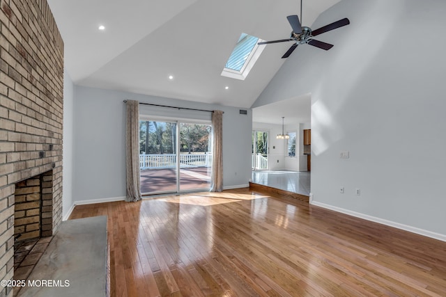 unfurnished living room with baseboards, high vaulted ceiling, hardwood / wood-style floors, and a fireplace