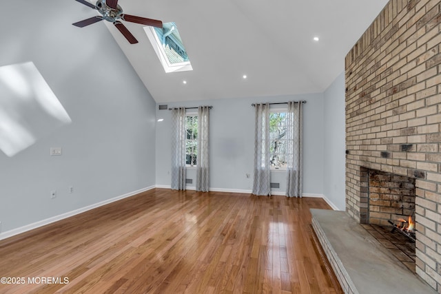 unfurnished living room featuring baseboards, high vaulted ceiling, a fireplace, ceiling fan, and light wood-type flooring