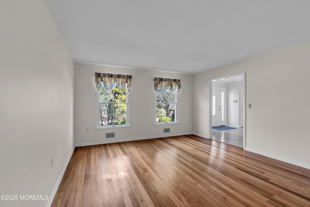 spare room with visible vents, baseboards, and wood-type flooring