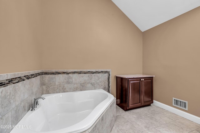 bathroom with visible vents, tile patterned floors, baseboards, vaulted ceiling, and a bath