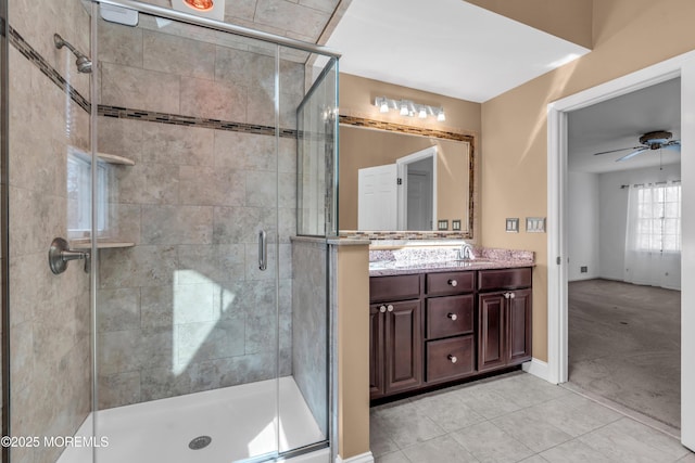 bathroom featuring a ceiling fan, double vanity, a stall shower, a sink, and tile patterned flooring