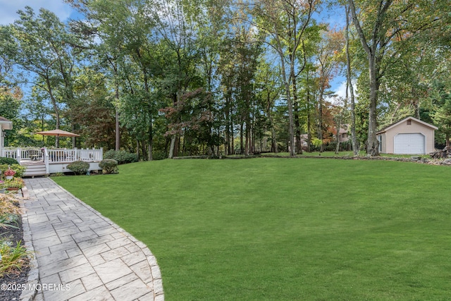 view of yard with a wooden deck, a detached garage, and an outdoor structure