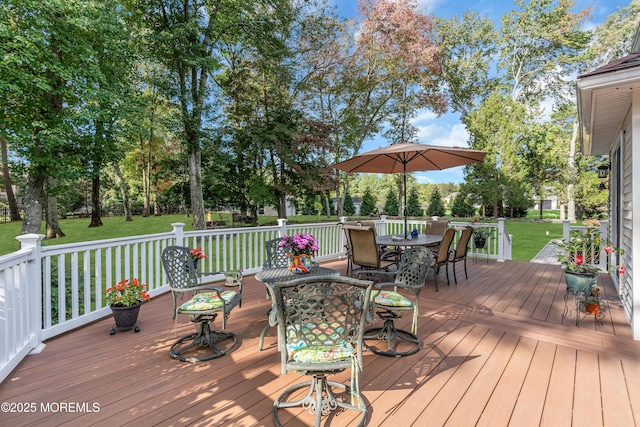 wooden deck with outdoor dining area and a yard