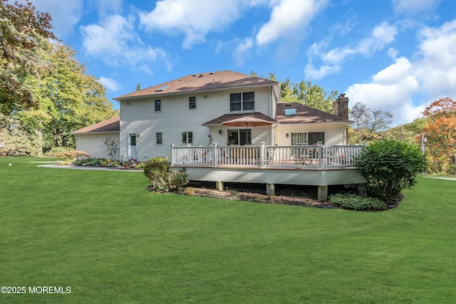 rear view of property with a yard, a deck, and a chimney