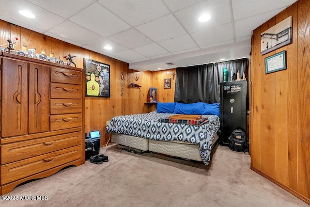 bedroom with carpet flooring, visible vents, a paneled ceiling, and wooden walls