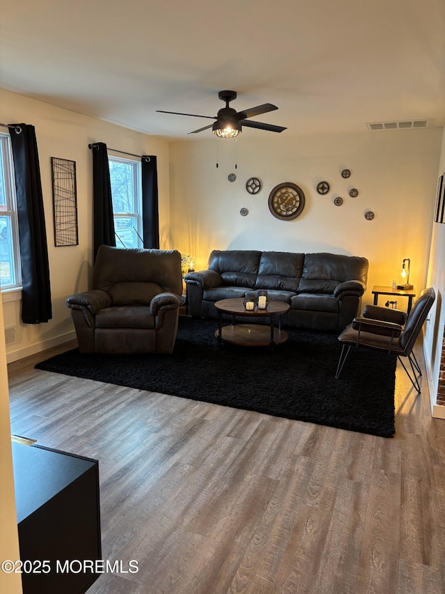 living area with a ceiling fan, wood finished floors, and visible vents