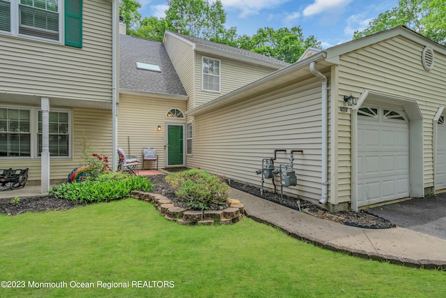 view of front of home featuring a front lawn, a garage, and a shingled roof