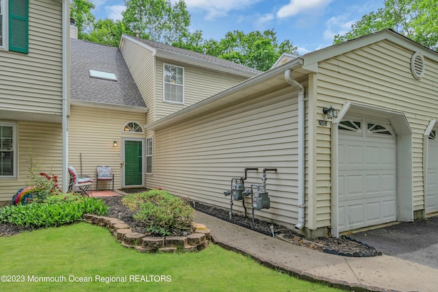 view of front of property featuring a garage, a front lawn, and a shingled roof