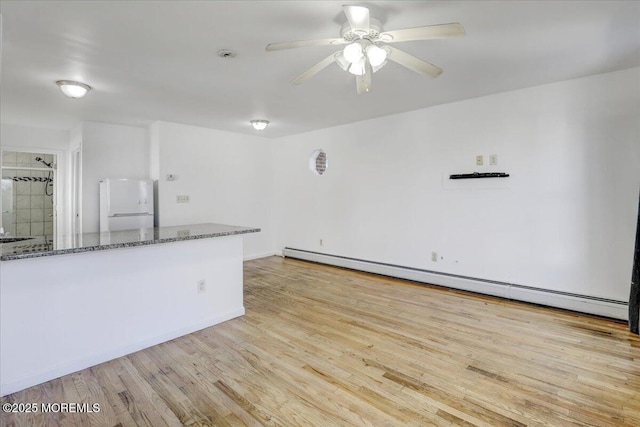 empty room with ceiling fan, a baseboard radiator, and wood finished floors