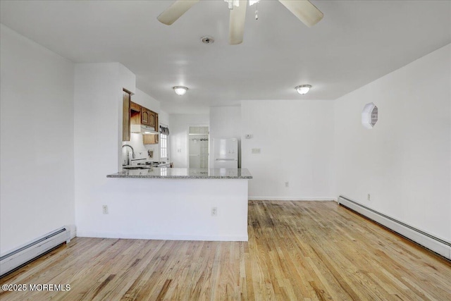 kitchen with under cabinet range hood, a baseboard heating unit, freestanding refrigerator, light wood finished floors, and baseboard heating