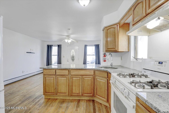 kitchen with a baseboard heating unit, under cabinet range hood, white gas range, a peninsula, and a sink