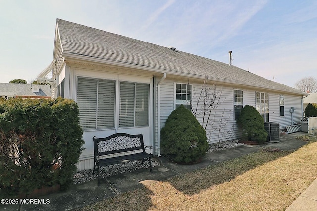 back of property featuring cooling unit and roof with shingles