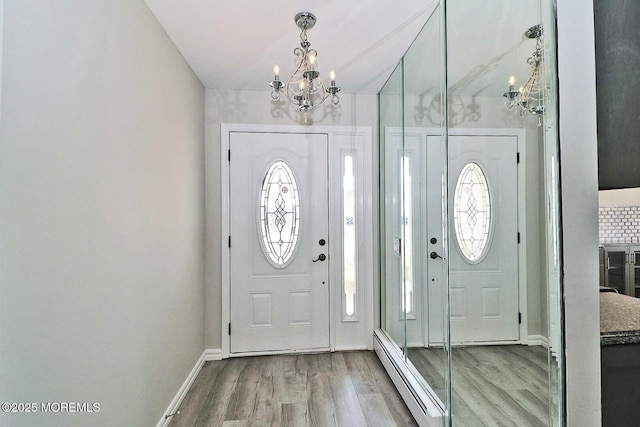 entryway featuring a baseboard heating unit, an inviting chandelier, wood finished floors, and a healthy amount of sunlight