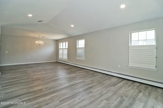 spare room with visible vents, lofted ceiling, baseboard heating, and wood finished floors