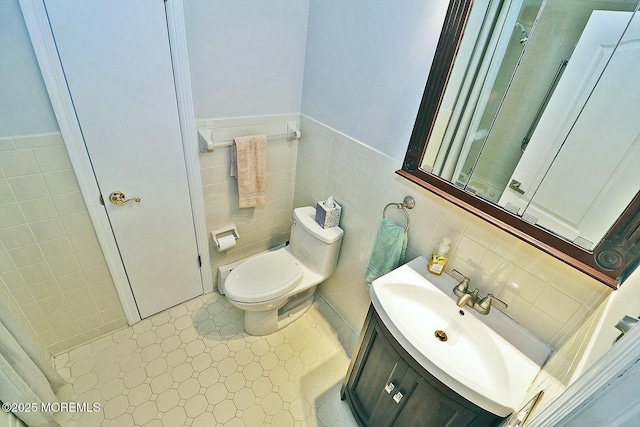 bathroom with tiled shower, toilet, tile walls, and vanity