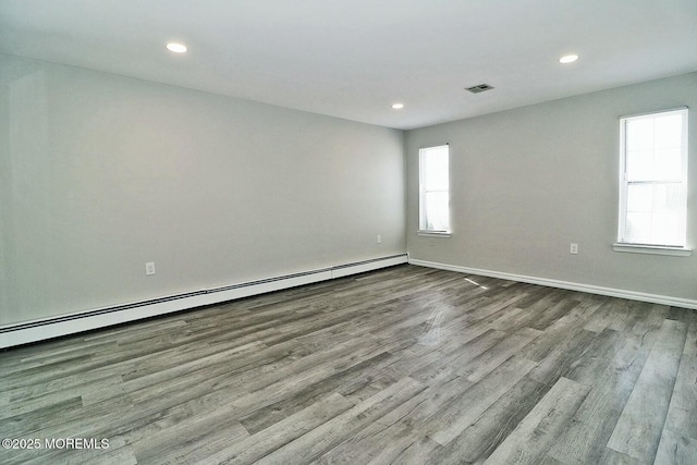 unfurnished room with wood finished floors, visible vents, baseboards, recessed lighting, and a baseboard heating unit