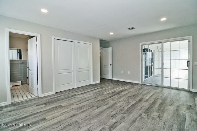 unfurnished bedroom featuring baseboard heating, recessed lighting, visible vents, and wood finished floors