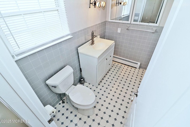 half bathroom with tile patterned flooring, tile walls, toilet, vanity, and a baseboard radiator