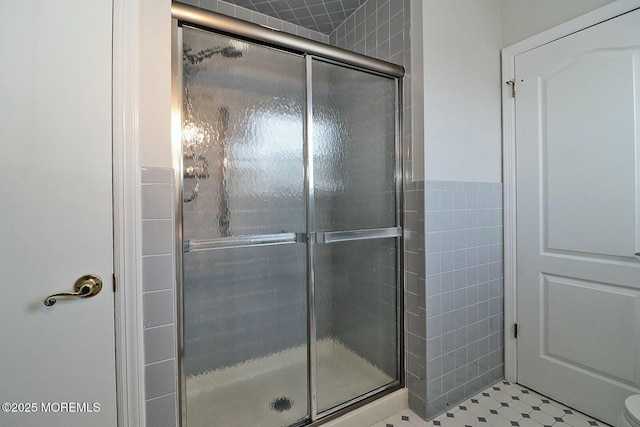 bathroom with tile patterned floors, a stall shower, and tile walls