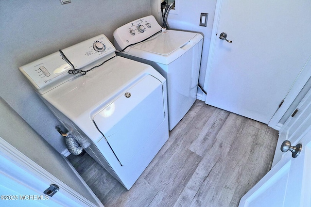 clothes washing area featuring laundry area, light wood-style flooring, and washer and clothes dryer