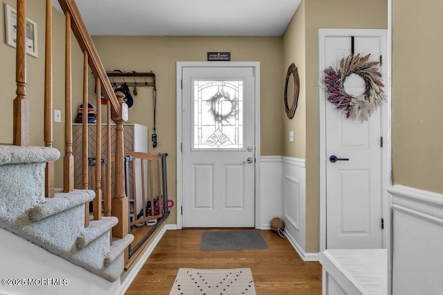 foyer entrance featuring stairway, wood finished floors, and wainscoting