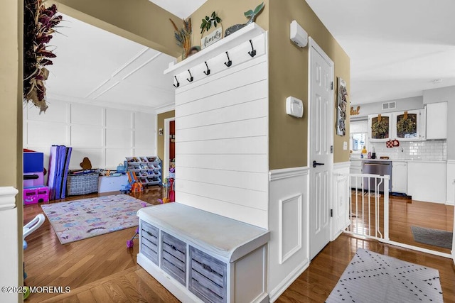 mudroom featuring a decorative wall, visible vents, and dark wood-type flooring