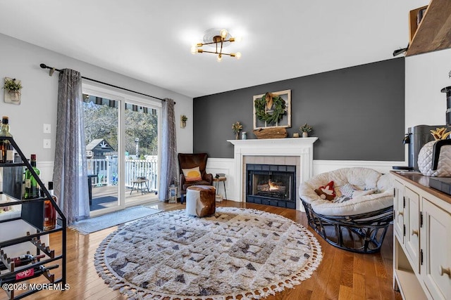 living room with wainscoting, a tile fireplace, and wood finished floors