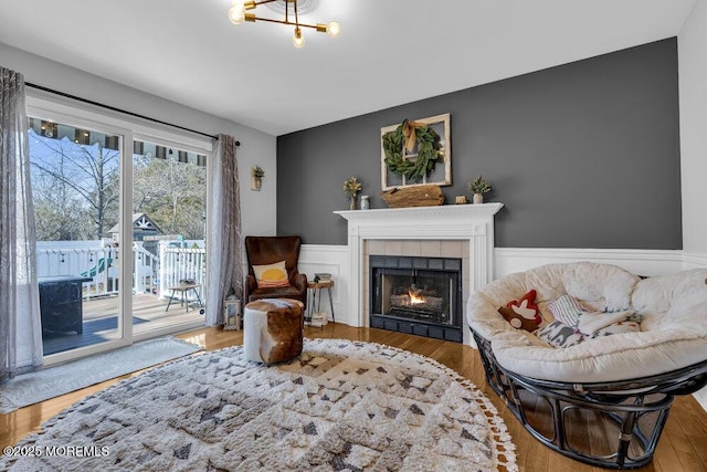 sitting room featuring wainscoting, wood finished floors, and a tiled fireplace