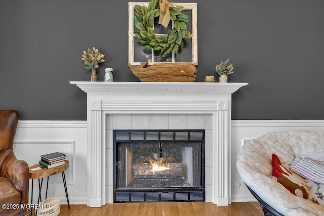 interior details featuring wood finished floors, a fireplace, and wainscoting