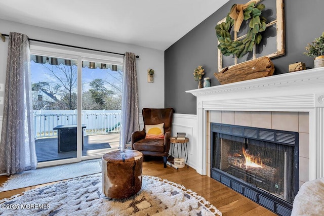 sitting room featuring a wainscoted wall, wood finished floors, a fireplace, and a decorative wall