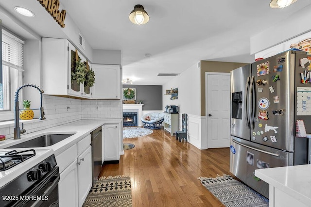 kitchen featuring light countertops, stainless steel appliances, wood finished floors, white cabinetry, and a sink