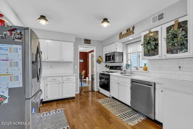 kitchen with wood finished floors, visible vents, stainless steel appliances, light countertops, and white cabinets