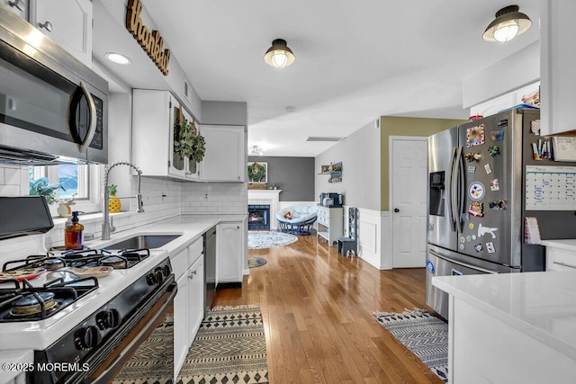 kitchen featuring a sink, light countertops, white cabinets, appliances with stainless steel finishes, and wainscoting