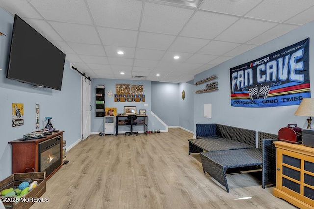 interior space with baseboards, a drop ceiling, a barn door, recessed lighting, and wood finished floors