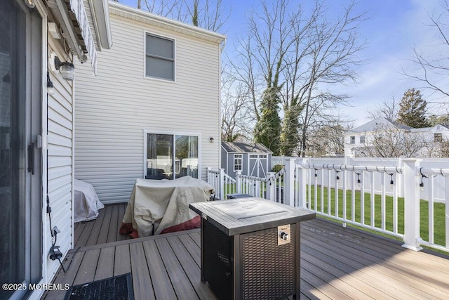 wooden terrace with a shed, a lawn, an outdoor structure, and fence