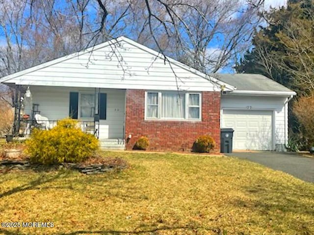 view of front of home with brick siding, a front lawn, covered porch, a garage, and driveway