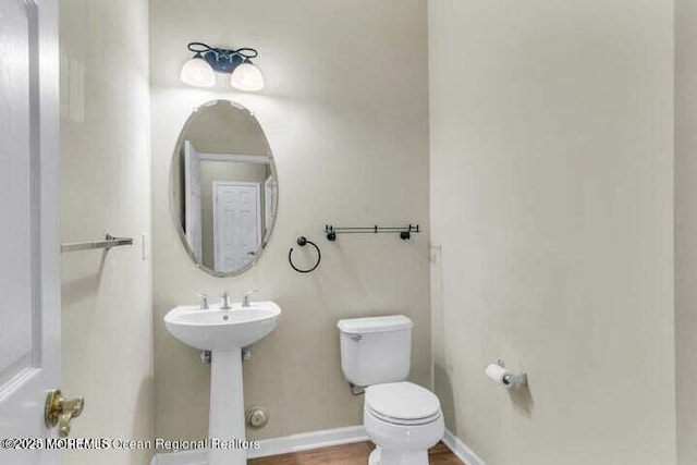 bathroom with a sink, toilet, baseboards, and wood finished floors