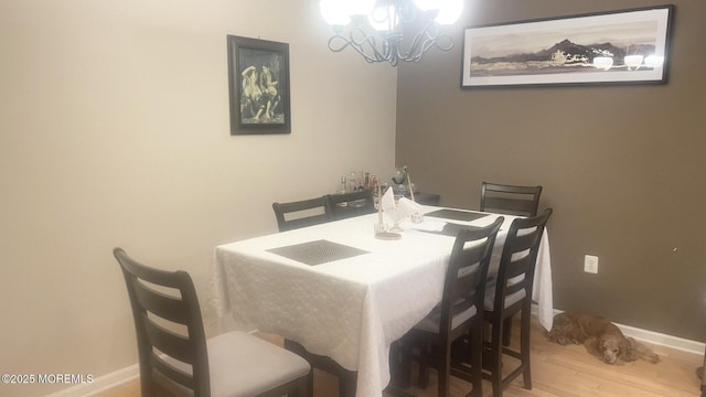 dining space featuring baseboards, an inviting chandelier, and wood finished floors