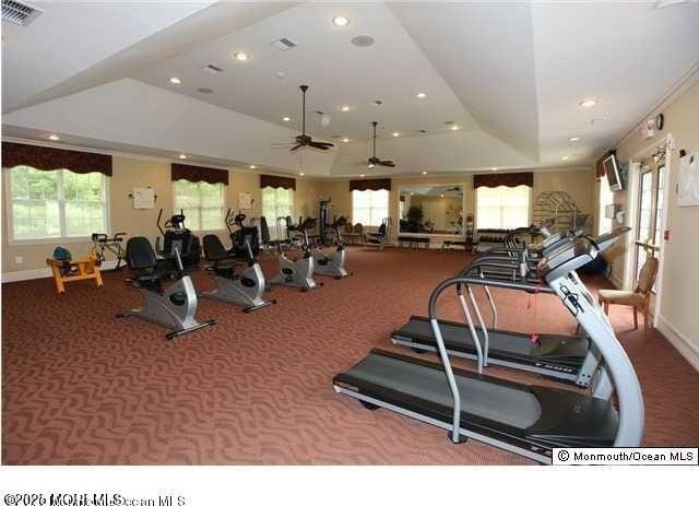 gym featuring a tray ceiling, carpet flooring, recessed lighting, and visible vents