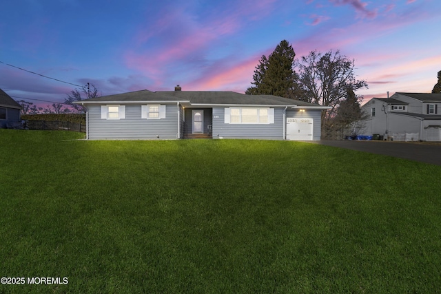 ranch-style house featuring a yard, a garage, and driveway