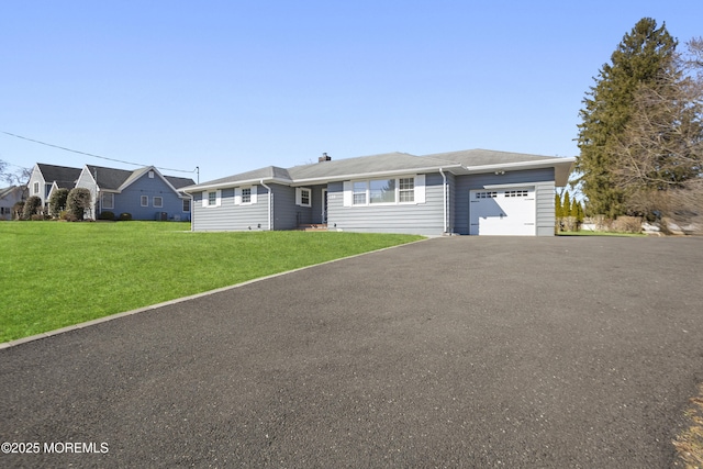 ranch-style home featuring a garage, a front lawn, and aphalt driveway