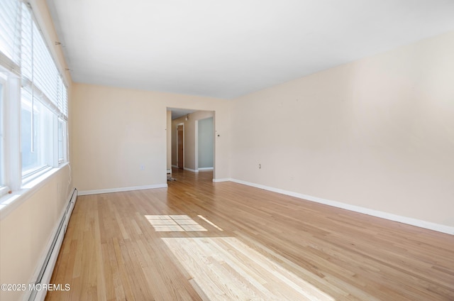 unfurnished room with light wood-style flooring, a healthy amount of sunlight, baseboards, and a baseboard radiator