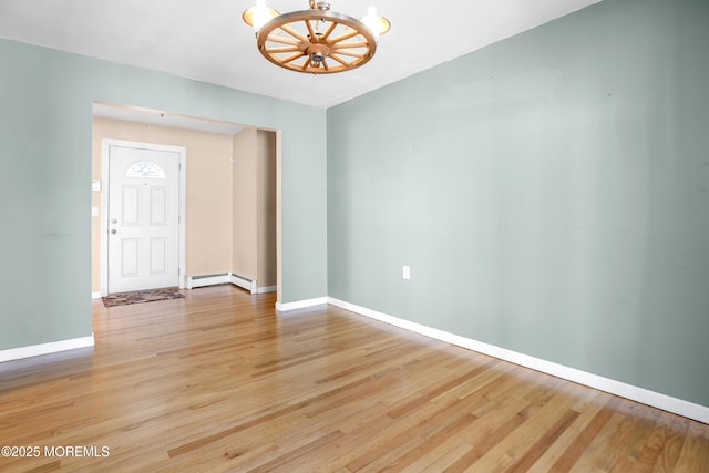 empty room with light wood finished floors, a baseboard heating unit, and baseboards