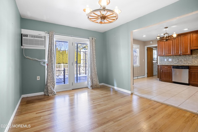 interior space featuring a notable chandelier, an AC wall unit, light wood-style flooring, decorative backsplash, and dishwasher